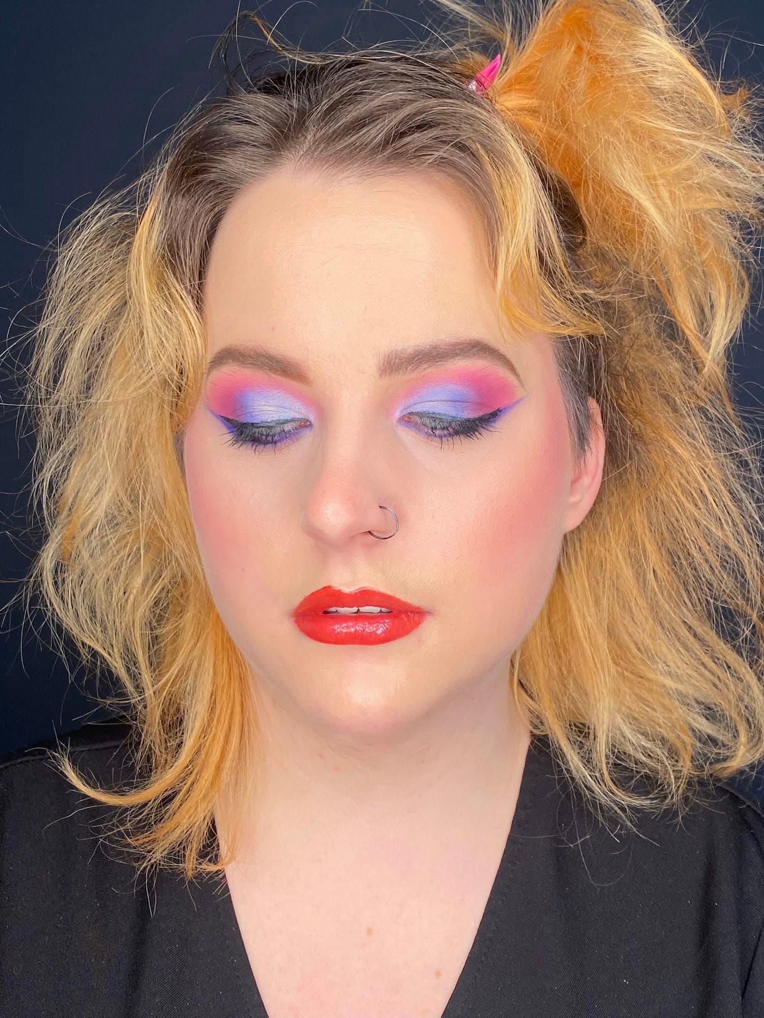 Bright glam makeup with pink and blue eyeshadow and red lip.